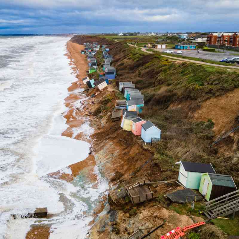 Casetas de playa caídas por los acantilados erosionados en Milford-on-Sea, Hampshire, mientras la costa sur fue golpeada por olas altas y mareas